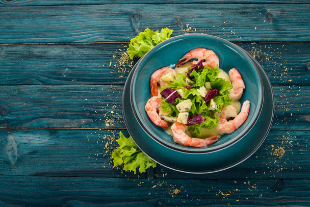 Royal prawns in creamy sauce and cheese. Seafood on a plate. Top view. On a blue wooden background. Copy space. - Fotoğraf, Görsel