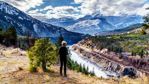 Mujer mayor mirando la vista de la garganta profunda del río Thompson a lo largo de la famosa ruta del cañón Fraser entre Cache Creek y Hope en Columbia Británica, Canadá
 - Foto, imagen
