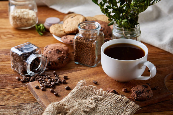 Coffee cup, jar with coffee beans, cookies over rustic background, selective focus, close-up, top view - Φωτογραφία, εικόνα