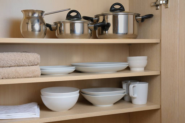 Different white dishes and pans in cupboard in the kitchen.Scandinavian style.Concept order in the cupboard in the kitchen.  - Photo, image