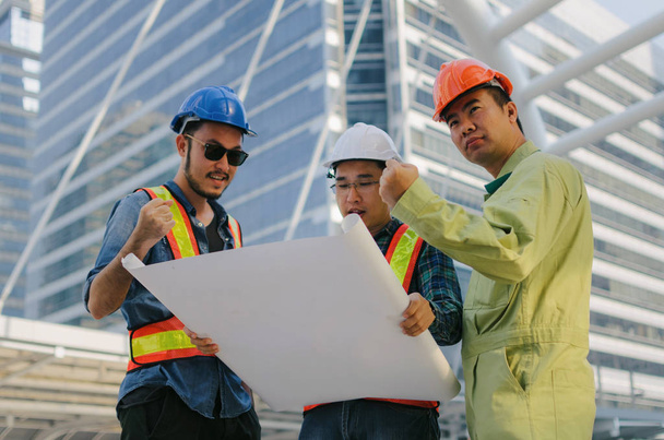 group of engineer, technician and architect planning about new project building plan with blueprint in modern city building background, contractor, construction site, business and industry concept - Foto, Imagen