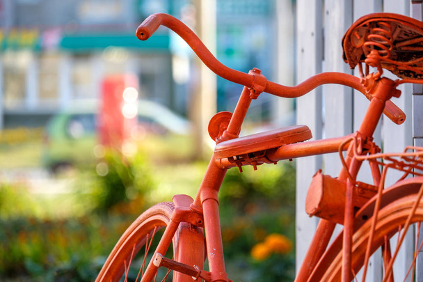 oranje fiets in de buurt van de muur op de achtergrond van de zomer de stad - Foto, afbeelding