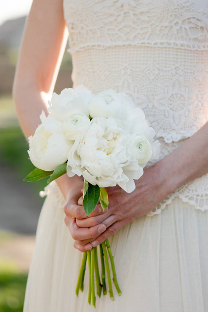 Νυφική ανθοδέσμη. Η νύφη κρατάει μπουκέτο λουλούδια peony. Όμορφη λευκή Παιώνια. - Φωτογραφία, εικόνα