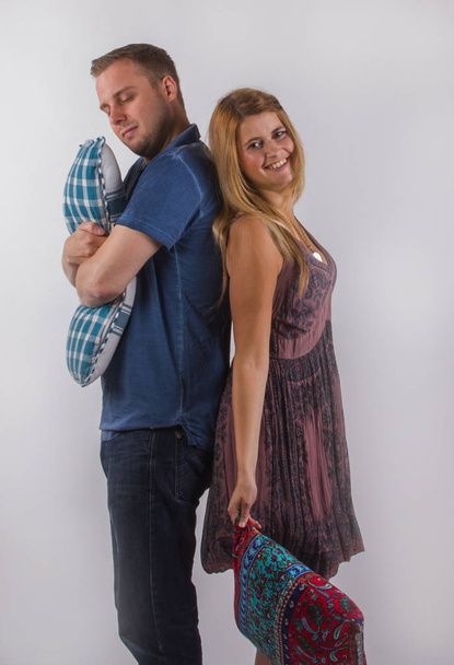 Νεαρό ζευγάρι στέκεται πλάτη με πλάτη με μαξιλάρια. Η έννοια της  - Φωτογραφία, εικόνα