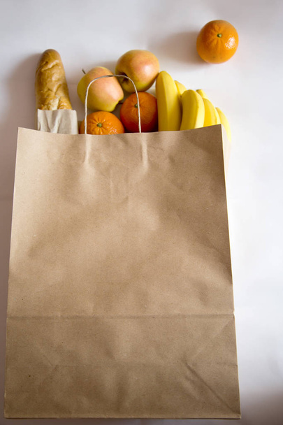 Paper bag of different fruits and bread on white wooden background. Flat lay. Top view. - Foto, immagini