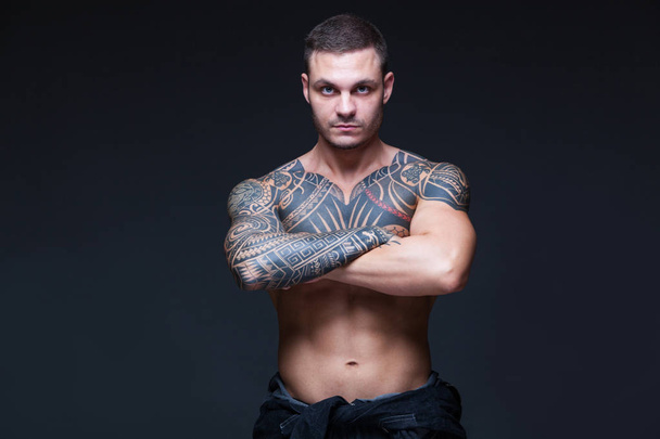 L'homme avec un torse nu musclé avec des tatouages sur le fond sombre. ABS
 - Photo, image