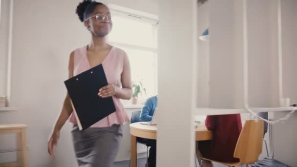 Szczęśliwy czarny kierownik kobiece kobieta inspiruje pracowników. Mieszane pochodzenie etniczne młodzieży uśmiechający się pracy w biurze modny nowoczesny loft 4k - Materiał filmowy, wideo