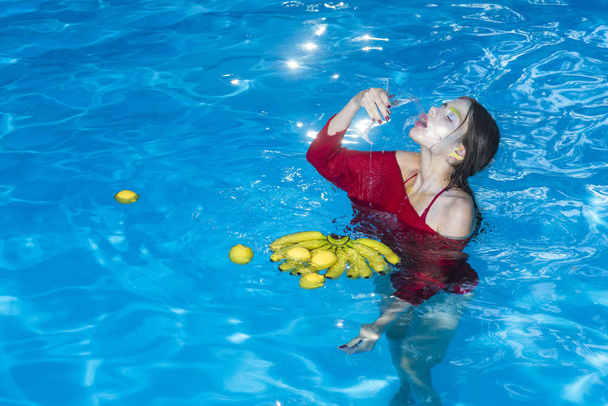 Vitamin in banana at girl sitting near water. Woman relax in spa pool. Summer vacation and travel to ocean. Dieting and healthy organic food, vegetarian. woman with tropical fruit in pool. - Foto, afbeelding