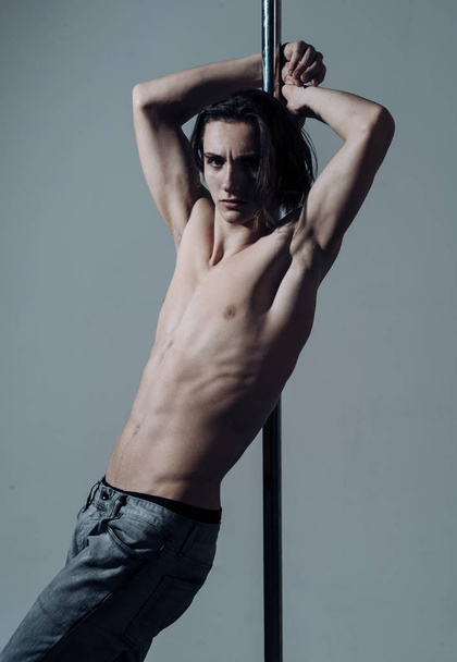 Sexy dancer concept. Sexy, attractive guy lean on metallic pole. - Foto, Bild