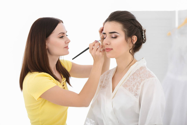 Professional makeup artist working with young woman in salon - Foto, Imagen