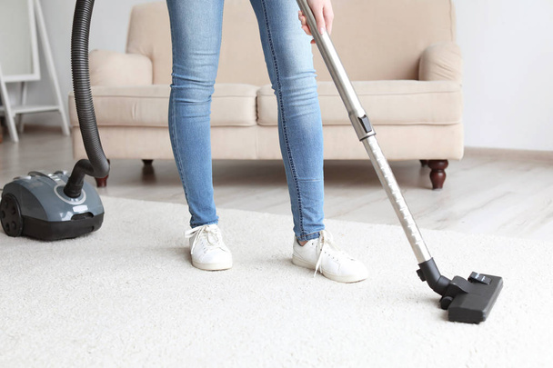 Woman cleaning carpet with vacuum in living room - Valokuva, kuva