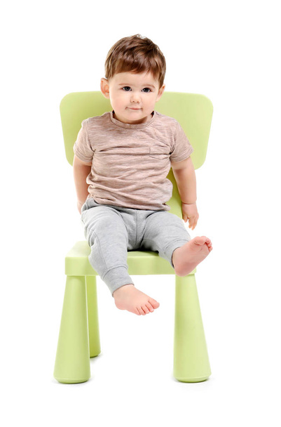 Cute baby sitting on chair against white background - Foto, imagen