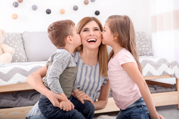 Cute little children kissing their nanny at home - Фото, изображение