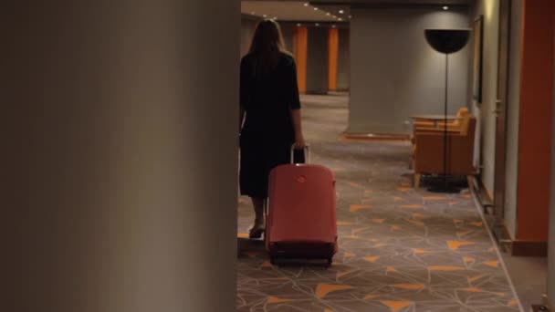 Mujer con maleta caminando a la habitación en el pasillo del hotel
 - Metraje, vídeo