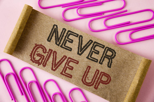 Tekst pisma ręcznego pisania Never Give Up. Pojęcia, co oznacza, być trwałe motywowania siebie nigdy nie uda spojrzenie powrotem napisane na karton składany kawałek papieru na zwykły tle w papier szpilki. - Zdjęcie, obraz