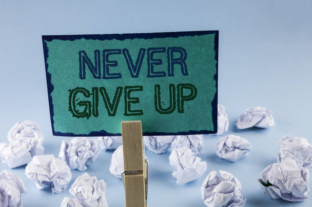 Текстовый знак "Никогда не сдавайся". Будьте настойчивы мотивировать себя преуспеть никогда не оглядываться назад, написанный на липкие бумагу для заметок холдинг клип на простом фоне
 - Фото, изображение