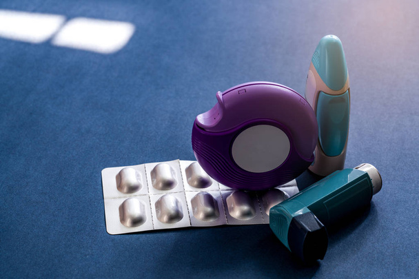 Set von Asthma-Inhalator, Akuhaler und Anti-Allergie-Pillen zur Behandlung von Asthma. Asthma-Controller, Entlastungsgeräte auf dunkelblauem Hintergrund. Bronchodilatator und Steroide bei schwerem Asthma.  - Foto, Bild