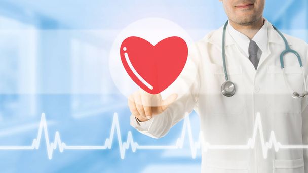 Doctor pointing at heart icon on blue background. - Photo, Image