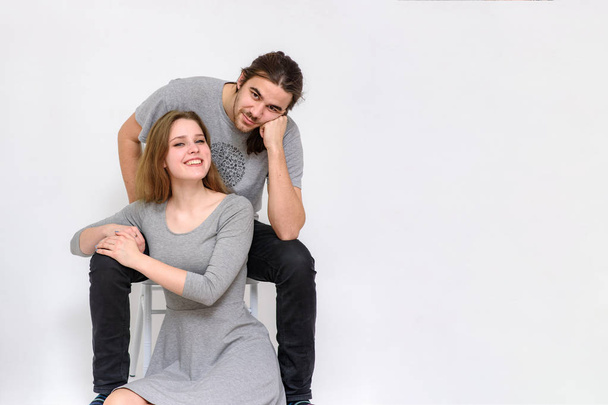 beautiful and young man and woman are sitting on a chair and on the floor in different poses - 写真・画像