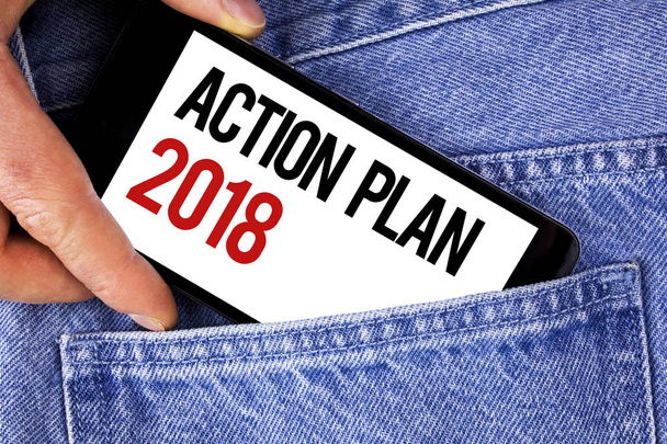Szöveg jel mutatja a cselekvési terv 2018. Fogalmi fénykép tervek célok tevékenységek élet célok javító fejlesztés írott-ra mozgatható telefon betöltő férfi farmer kék háttér. - Fotó, kép
