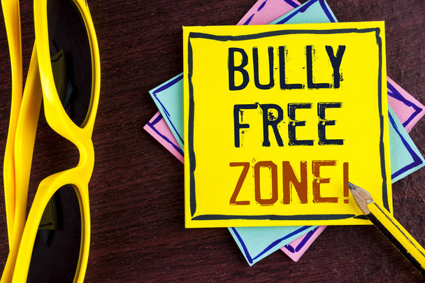 Text sign showing Bully Free Zone Motivational Call. Conceptual photo creating abuse free school college life written on Yellow Sticky note paper on wooden background Pencil Sun Glasses. - Photo, Image