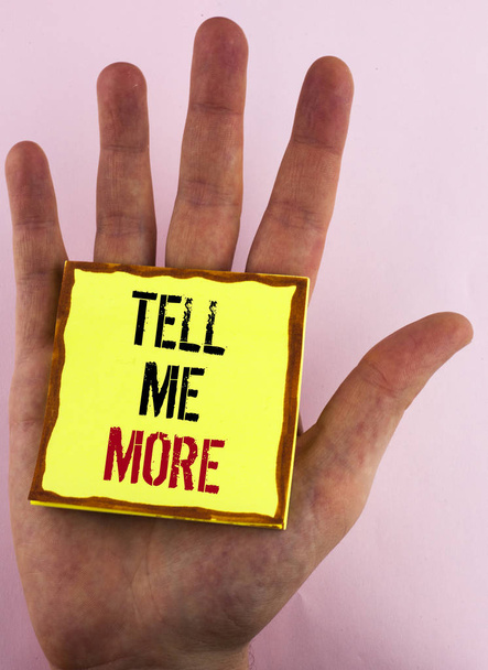 Tell Me More Wyświetlono znak tekstu. Koncepcyjne zdjęcie Elaborate biznes myśli dalszej pomocy napisane na żółtym papierze Uwaga Sticky umieszczone na dłoni na tle zwykłego. - Zdjęcie, obraz