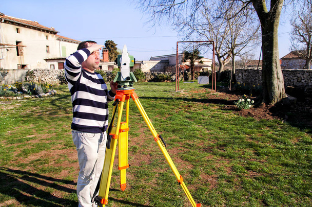 Trabalhador do topógrafo fazendo medições no jardim, estação total
 - Foto, Imagem