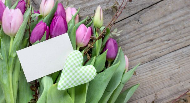 piękny bukiet tulipanów różowe i fioletowe z sercem i czarno-białych spacji na podłoże drewniane - Zdjęcie, obraz