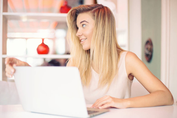 uma bela jovem feliz sorridente empresária está olhando para alguém trabalhando em um laptop em um café acolhedor pela manhã
 - Foto, Imagem