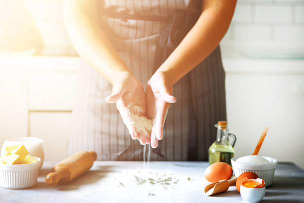 Female hands kneading dough, baking background. Cooking ingredients - eggs, flour, sugar, butter, milk, rolling pin on white style kitchen. Copy space - Foto, Imagem