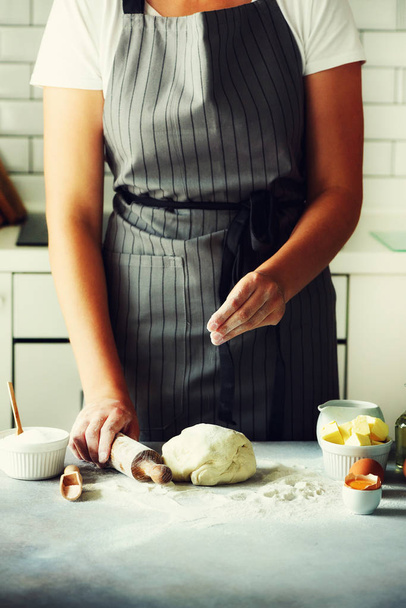 Female hands kneading dough, baking background. Cooking ingredients - eggs, flour, sugar, butter, milk, rolling pin on white style kitchen. Copy space - Foto, imagen