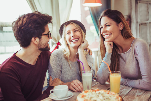 Nuoret ystävät jakavat pizzaa kahvilassa
 - Valokuva, kuva