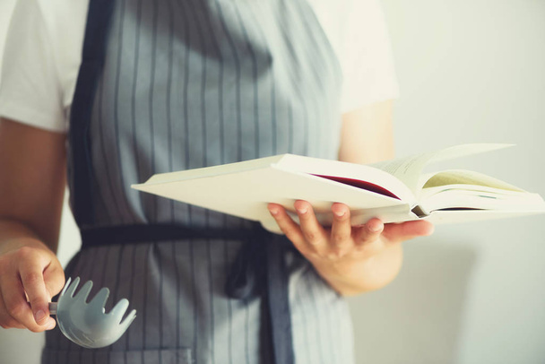 Girl wearing grey apron and reading book. Lifestyle concept - Фото, зображення