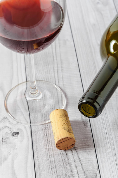 Red wine in a glass and a bottle on a light wooden table - Photo, image