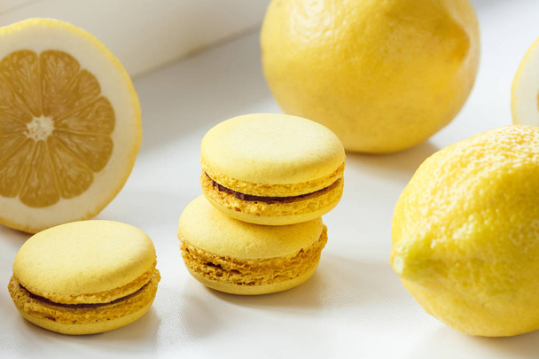 Yellow french macarons with lemons on the table - Fotó, kép