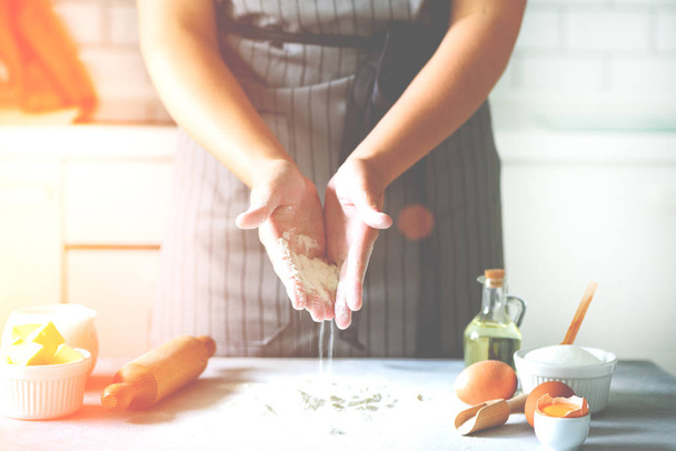 Female hands kneading dough, baking background. Cooking ingredients - eggs, flour, sugar, butter, milk, rolling pin on white style kitchen. Copy space - 写真・画像