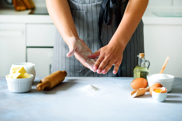 Female hands kneading dough, baking background. Cooking ingredients - eggs, flour, sugar, butter, milk, rolling pin on white style kitchen. Copy space - Fotografie, Obrázek