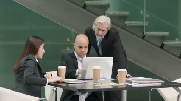 tre dirigenti aziendali si riuniscono in ufficio discutendo di affari utilizzando il computer portatile
. - Filmati, video