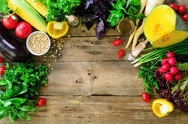 Vegetables on wooden background. Herbs, basil, onion, pumpkin, pine nuts, tomatoes, corn, radish, eggplant, bell pepper, salt, spices, oil, spinach, parsley, lettuce leaves. Top view, copy space - Φωτογραφία, εικόνα