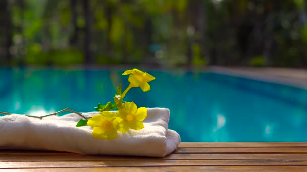 Closeup of female hand moving cocktail in glass jar , close to towel with branch of yellow flowers. Hotel pool background - Footage, Video