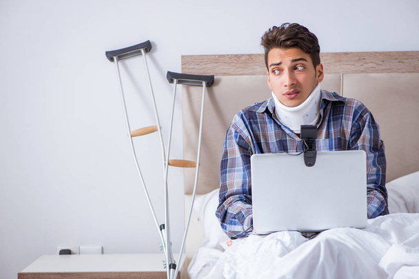Hombre lesionado charlando en línea a través de la webcam en la cama en casa - Foto, imagen