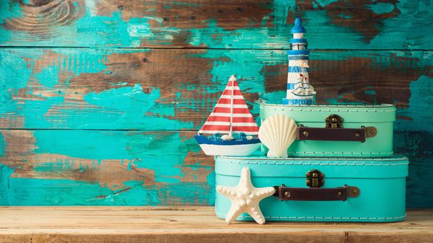 Suitcase boxes, boat and lighthouse decor over wooden background. Summer vacation concept - Foto, imagen