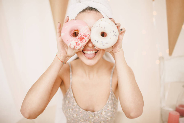 Funny girl with doughnuts instead of her eyes and in the turban in pink cute room - Fotografie, Obrázek