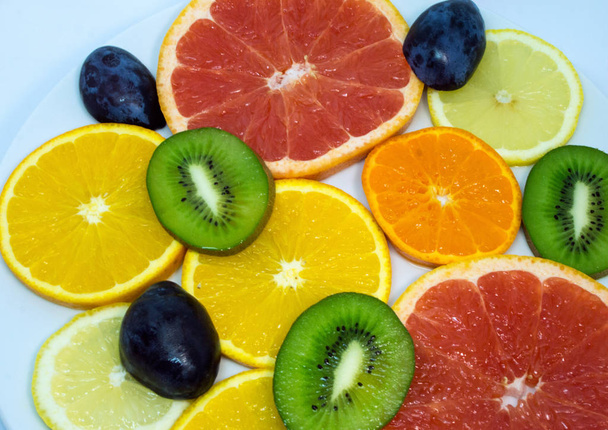 Colorful of cut fruits close up. Vegetarian food on the plate.  - Foto, Imagen