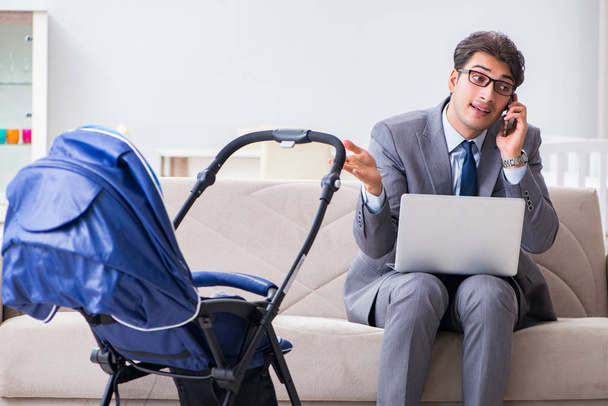 Businessman looking after newborn baby at home and teleworking - Photo, Image