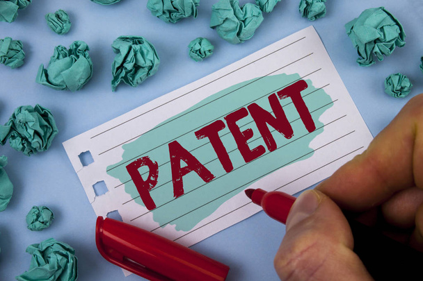Text sign showing Patent. Conceptual photo License that gives rights for using selling making a product written by Man on Painted Notepad Paper holding Marker plain background Paper Balls. - Photo, Image