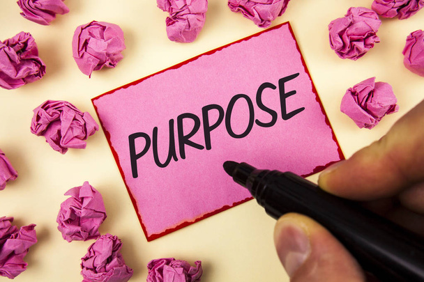 Text sign showing Purpose. Conceptual photo Reason for doing something Desired Goal Target Planned Achievement written by Man on Sticky Note paper holding Marker on plain background Paper Balls. - Photo, Image