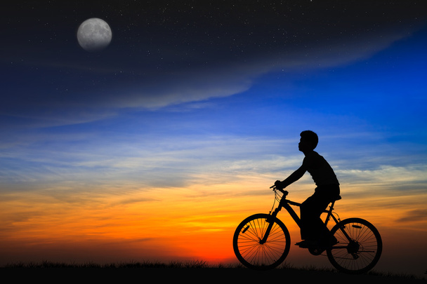 Silhouette boy riding a bicycle on the sunset - Photo, Image