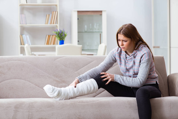 Jonge vrouw met gebroken been thuis - Foto, afbeelding
