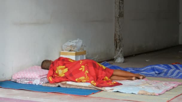 Dakloze man slaapt in rode sluier op de stad straat. Het probleem van de armoede in de wereld - Video
